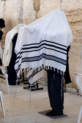 Some tallits (prayer shawls) are large enough to be draped over the head while praying. In the photo above, the tzitzit are visible on the four corners of the garment hanging down.