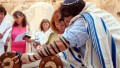 A woman reads from the Torah scroll in Jerusalem near the Western (Wailing) Wall. (Photo by Josh Evnin)