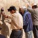 Siddur-Jewish prayer at the Western (Wailing) Wall in Jerusalem. The man wearing tefillin (phylacteries) is reading from a Siddur.