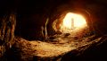 Man standing at entrace of cave looking out.